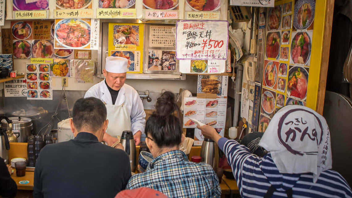 People eating at an outdoor sushi stall