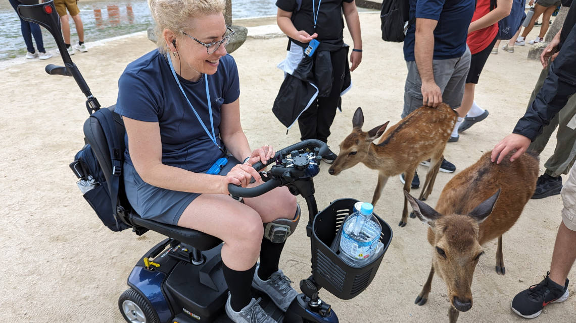 Anne de Ridder in her mobility scooter with deer from Miyajima in Hiroshima