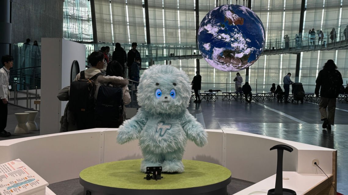 Furry robot in the foreground with large globe in the background