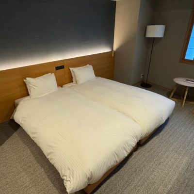 The main bedroom of the Two Bedroom Theater Suite has two twin beds, Japanese style-window covering, flatscreen TV on the wall and a closet.